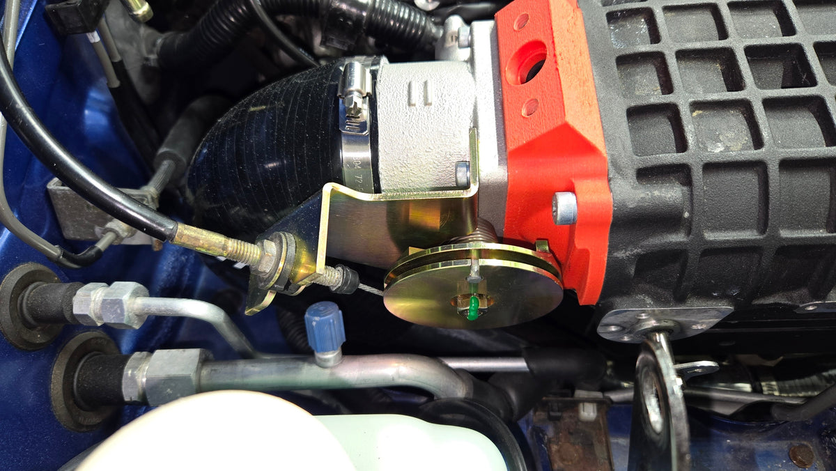 Close-up of the coldside intake hose connection at the supercharger inlet beside the bypass actuator