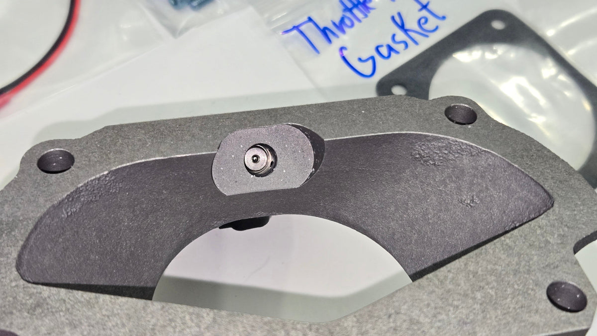Close-up of the E-Cool injector tip protruding through the cast adapter beside the throttle-body gasket