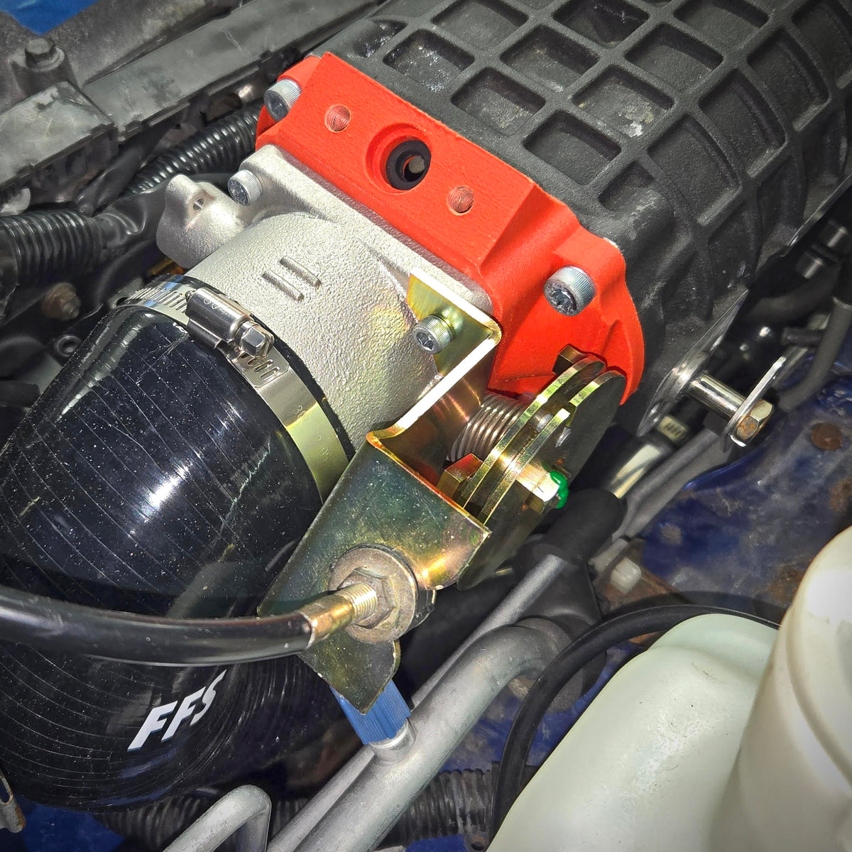 Isometric view of the installed throttle cable bracket upgrade beside the orange throttle-body adapter