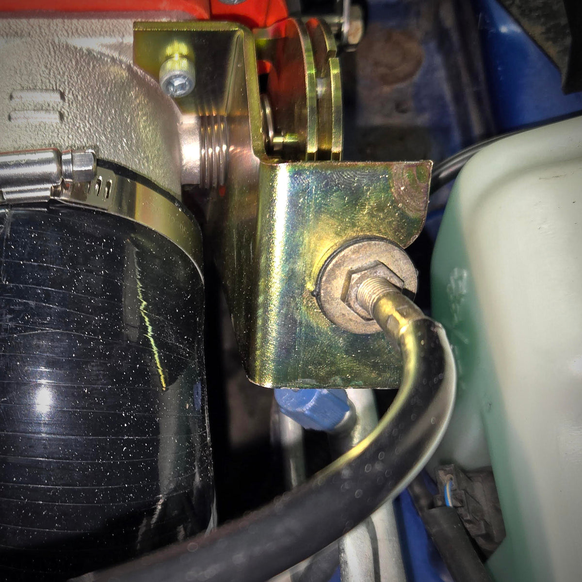 Rear view of the installed throttle cable bracket upgrade, showing the cable and support plate