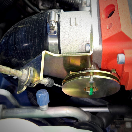 Side view of the throttle cable bracket upgrade installed below the throttle body, showing the cable-adjustment hardware