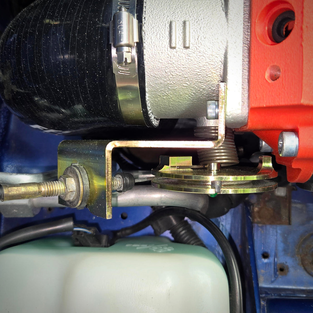 Top view of the installed throttle cable bracket upgrade, showing the cable attachment and bracket alignment under the throttle body