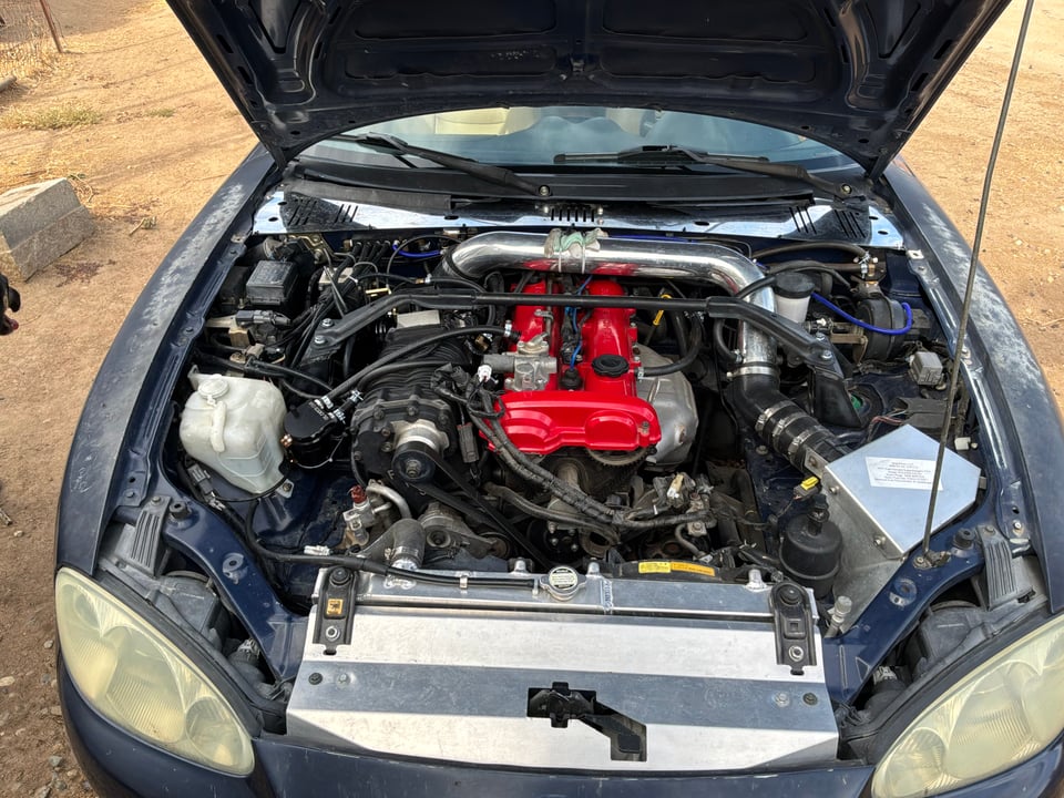 Front view of Nathaniel's blue 2001 Miata engine bay with an FFS MP62 supercharger kit